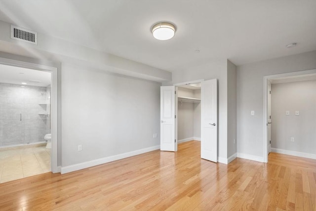 unfurnished bedroom with light wood finished floors, a closet, visible vents, ensuite bathroom, and baseboards