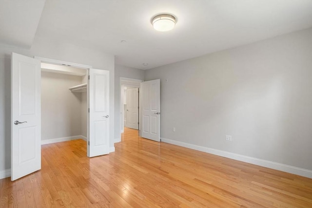 unfurnished bedroom with a closet, baseboards, and light wood finished floors