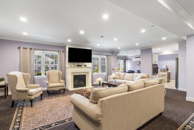 living room featuring a fireplace with flush hearth, baseboards, crown molding, and recessed lighting