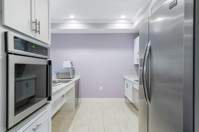 kitchen featuring stainless steel appliances, light countertops, white cabinets, and crown molding