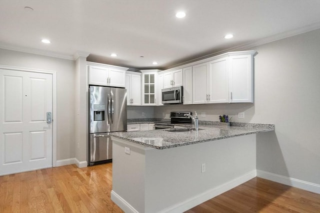 kitchen with a peninsula, light wood-type flooring, light stone counters, and stainless steel appliances