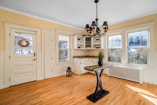 dining area featuring radiator heating unit, light wood-style flooring, and crown molding