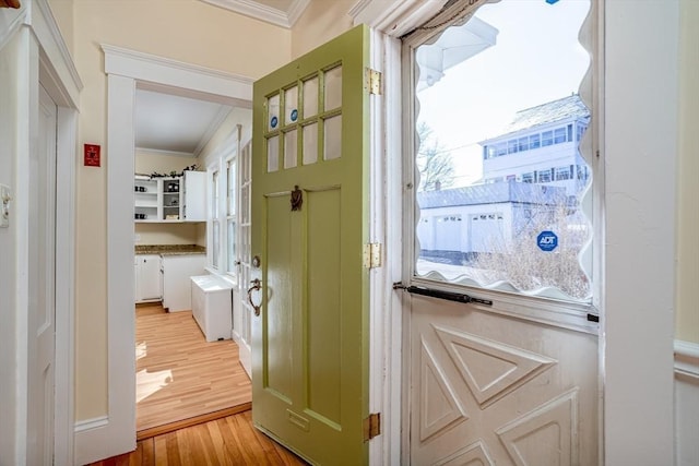 entryway featuring light wood finished floors and ornamental molding