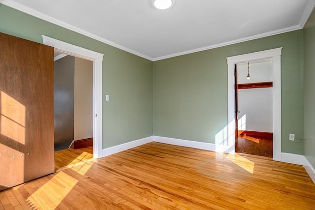 unfurnished room featuring ornamental molding, baseboards, and hardwood / wood-style flooring