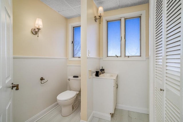 bathroom with toilet, baseboards, a closet, and wood finished floors