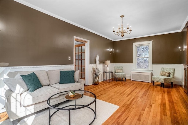 living room with light wood-type flooring, radiator heating unit, ornamental molding, and a chandelier