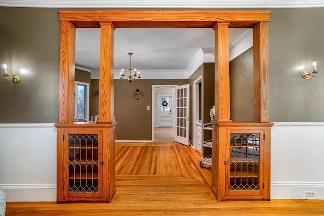 interior space featuring light wood-style floors, crown molding, baseboards, and an inviting chandelier