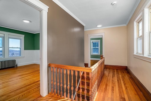 corridor featuring an upstairs landing, crown molding, radiator heating unit, and wood finished floors