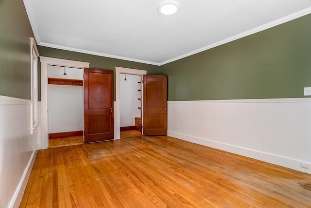 spare room with baseboards, ornamental molding, and light wood-style floors