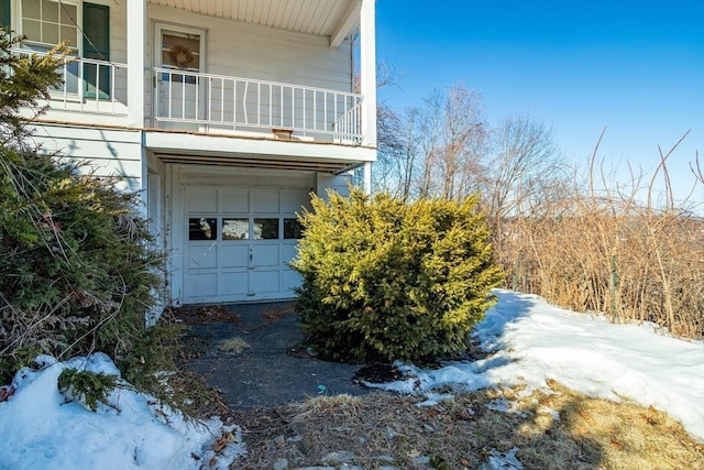 view of snowy exterior featuring a garage and a balcony