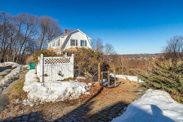 view of property exterior with a chimney, fence, and a gambrel roof