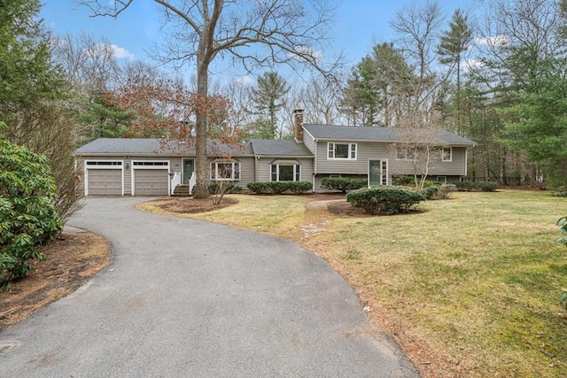split foyer home with a front lawn, driveway, a chimney, and a garage