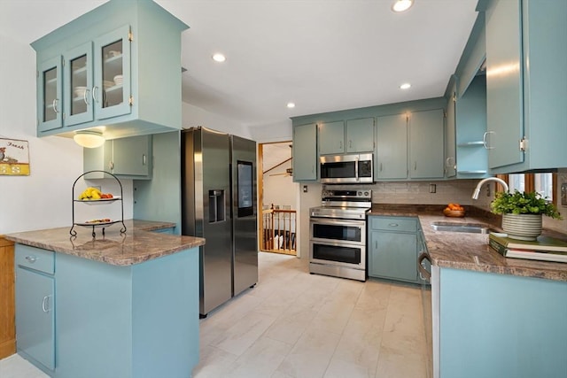 kitchen with a peninsula, stainless steel appliances, recessed lighting, tasteful backsplash, and a sink
