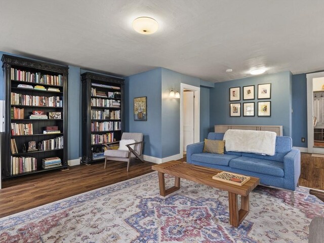 living room featuring wood finished floors, baseboards, and built in shelves