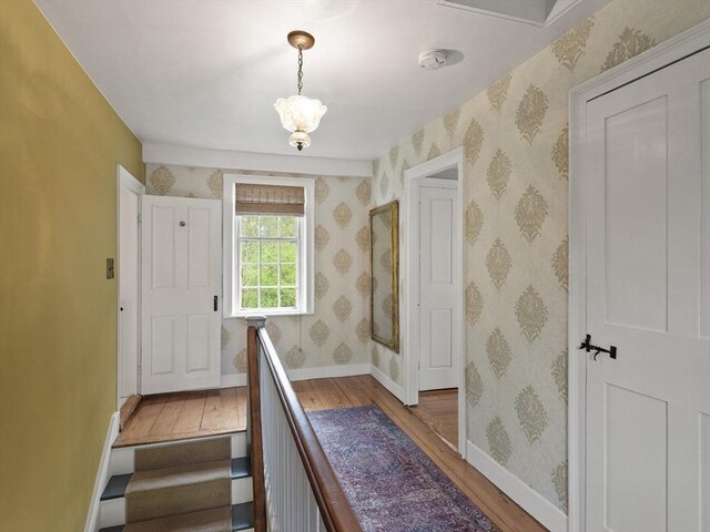 stairway with wood-type flooring, baseboards, and wallpapered walls