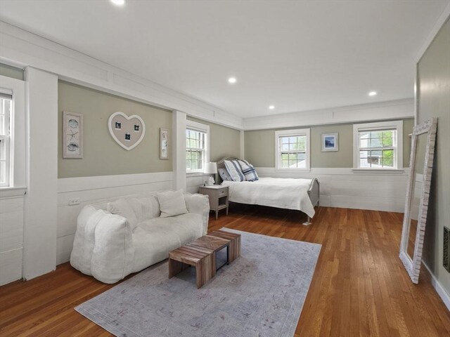 bedroom with wood finished floors, multiple windows, wainscoting, recessed lighting, and ornamental molding