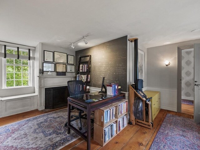 office area with wood-type flooring, a fireplace, and track lighting