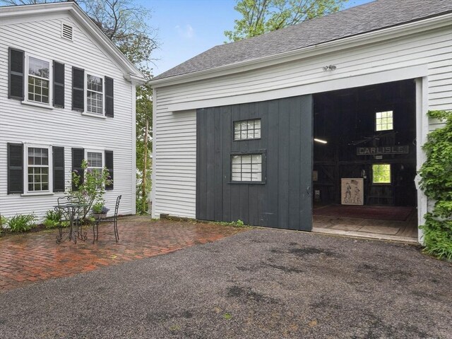 view of property exterior featuring a patio area and roof with shingles