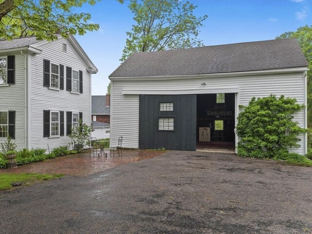 view of front of house featuring an outdoor structure and roof with shingles