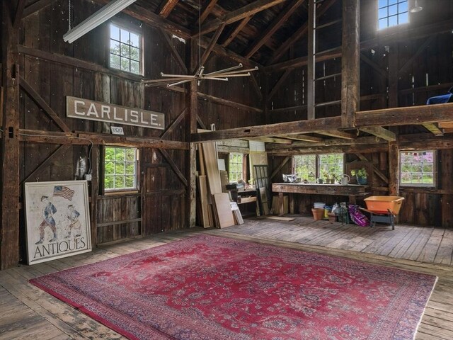 miscellaneous room with wood-type flooring, wooden walls, plenty of natural light, and a towering ceiling