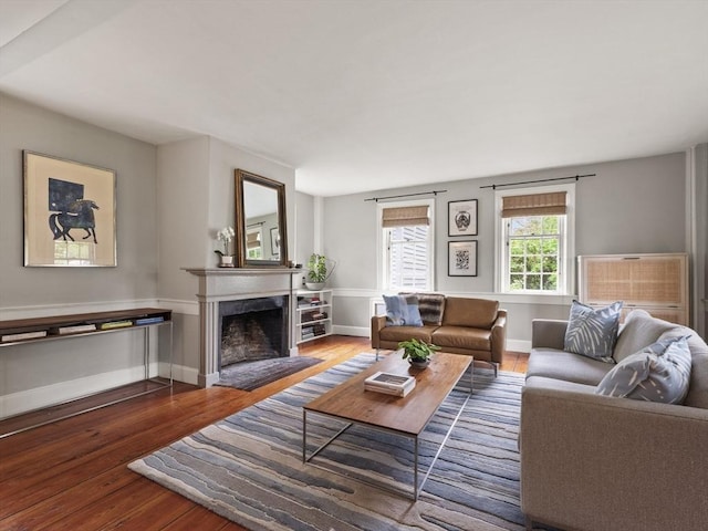 living area featuring wood-type flooring, a fireplace with flush hearth, and baseboards