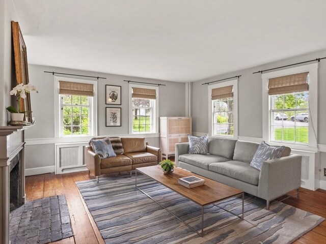 living room featuring wood-type flooring, a fireplace, and baseboards