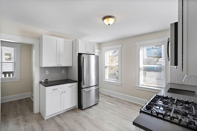 kitchen with dark countertops, light wood finished floors, white cabinets, and freestanding refrigerator