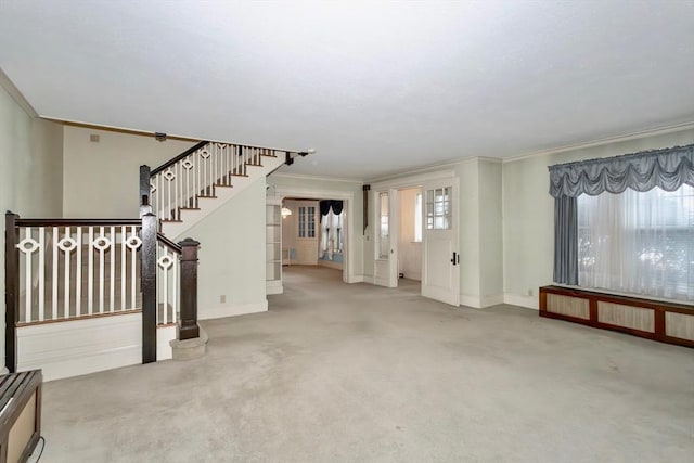 carpeted entrance foyer featuring crown molding and radiator