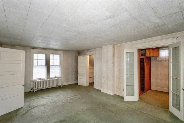 unfurnished bedroom featuring multiple windows, carpet flooring, radiator heating unit, and french doors