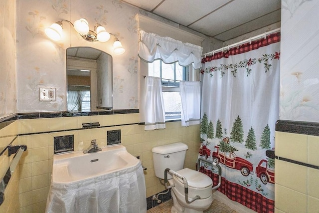 bathroom featuring walk in shower, sink, tile walls, and toilet