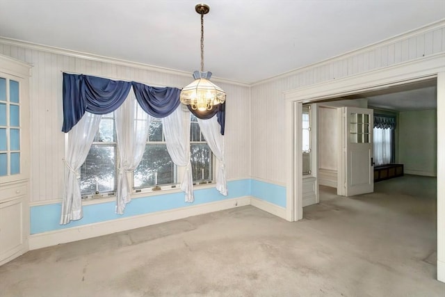 unfurnished dining area featuring light carpet, ornamental molding, and an inviting chandelier