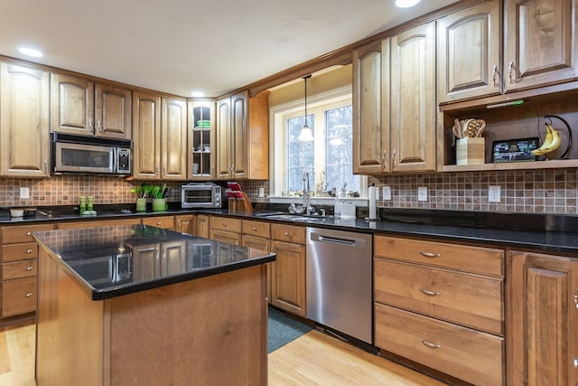 kitchen featuring hanging light fixtures, backsplash, black appliances, light hardwood / wood-style floors, and sink