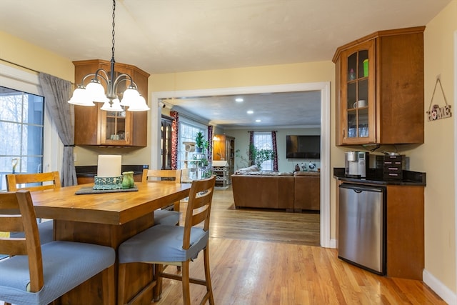 dining area with a wealth of natural light, light wood-type flooring, and an inviting chandelier