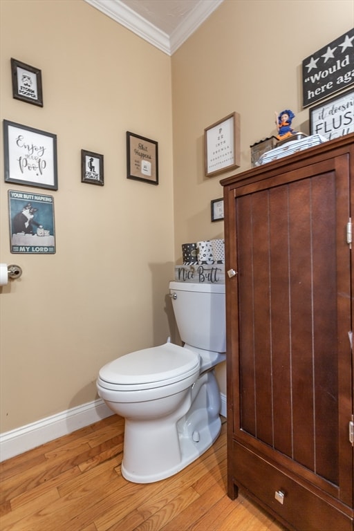 bathroom with toilet, hardwood / wood-style floors, and crown molding