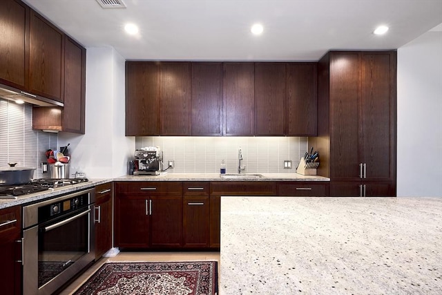 580 Washington St Unit 10A, Boston, MA 02111 - kitchen featuring appliances with stainless steel finishes, a sink, tasteful backsplash, light stone counters, and recessed lighting