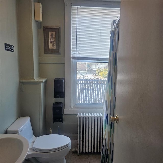 bathroom with tile patterned floors, radiator heating unit, toilet, and sink