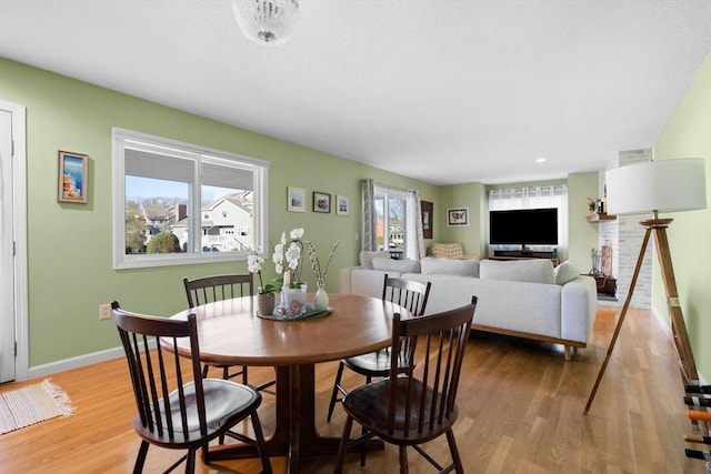 dining room with light hardwood / wood-style floors and a fireplace