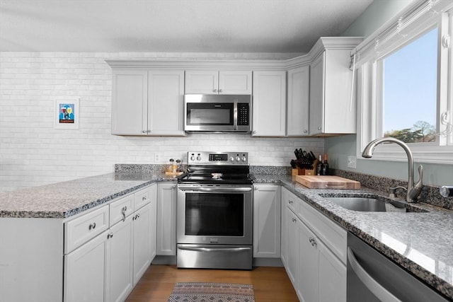 kitchen featuring white cabinets, light stone counters, sink, and stainless steel appliances