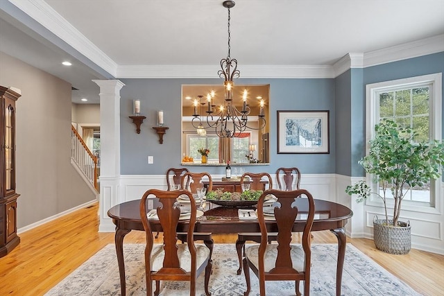 dining area with decorative columns, ornamental molding, an inviting chandelier, and light wood-type flooring