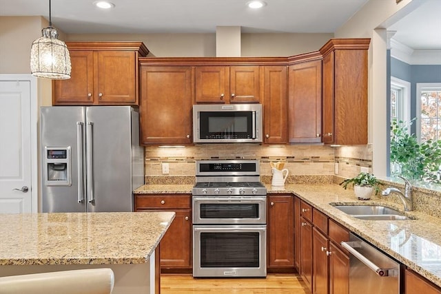 kitchen featuring appliances with stainless steel finishes, pendant lighting, tasteful backsplash, sink, and light stone countertops