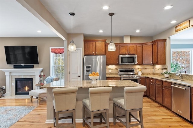 kitchen featuring a kitchen island, appliances with stainless steel finishes, decorative light fixtures, sink, and a kitchen breakfast bar