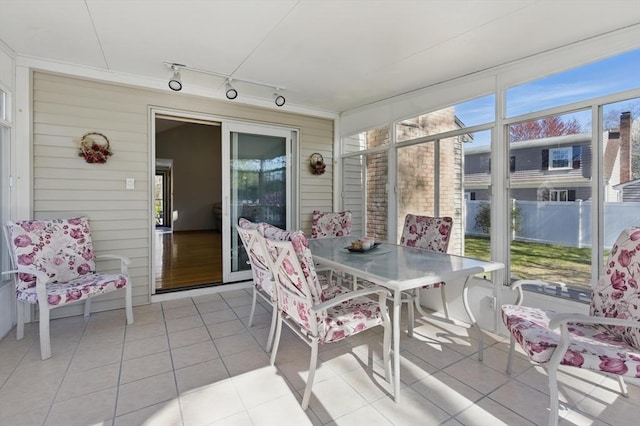sunroom with outdoor dining space, rail lighting, and a healthy amount of sunlight