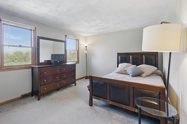 bedroom featuring baseboards, visible vents, light carpet, and a textured ceiling