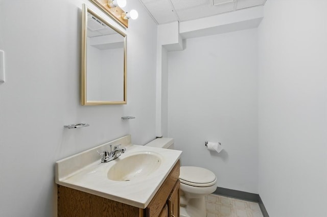 half bathroom with toilet, tile patterned floors, vanity, and baseboards