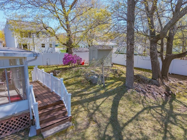 view of yard featuring an outdoor structure, a storage shed, a deck, and a fenced backyard