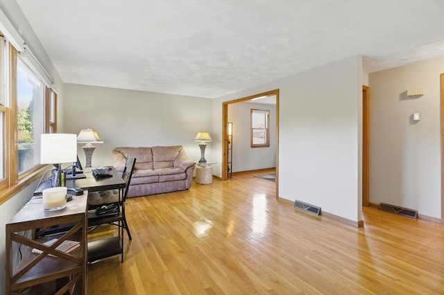 living room featuring visible vents, baseboards, and light wood-style floors