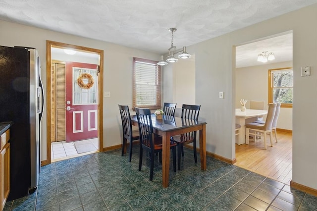dining room featuring dark tile patterned flooring, a notable chandelier, and baseboards