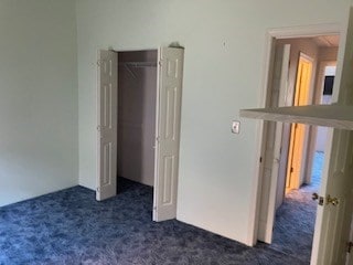 unfurnished bedroom featuring dark carpet and a closet