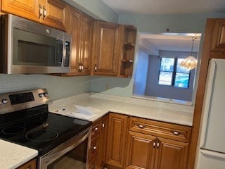 kitchen with appliances with stainless steel finishes, a notable chandelier, and pendant lighting