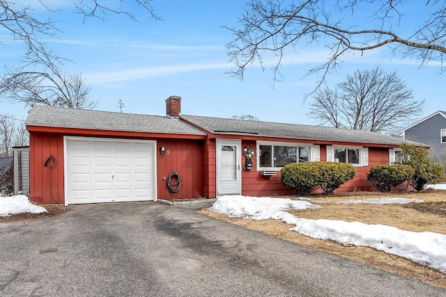 single story home featuring aphalt driveway, an attached garage, a shingled roof, board and batten siding, and a chimney